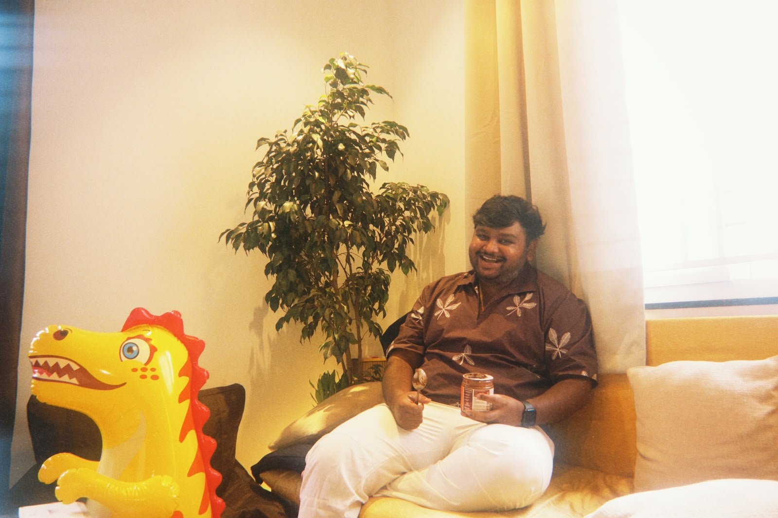 Nikith on the community-house couch with a jar of peanut butter and an inflatable dinosaur